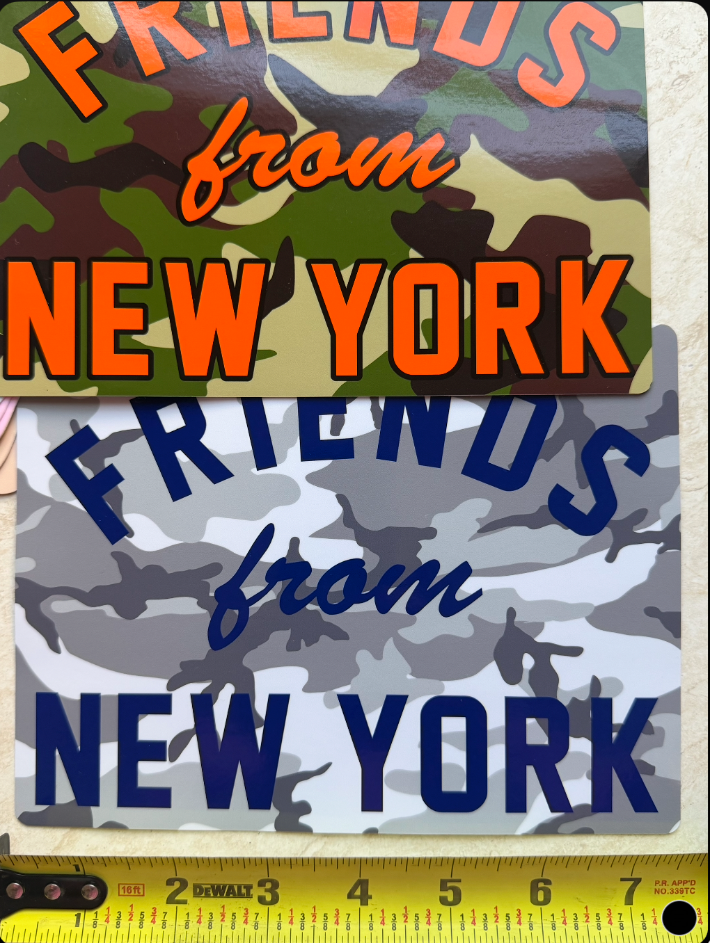 Oversized Friends From New York vinyl sticker in woodland camouflage with white lettering, shown beside a measuring tape.